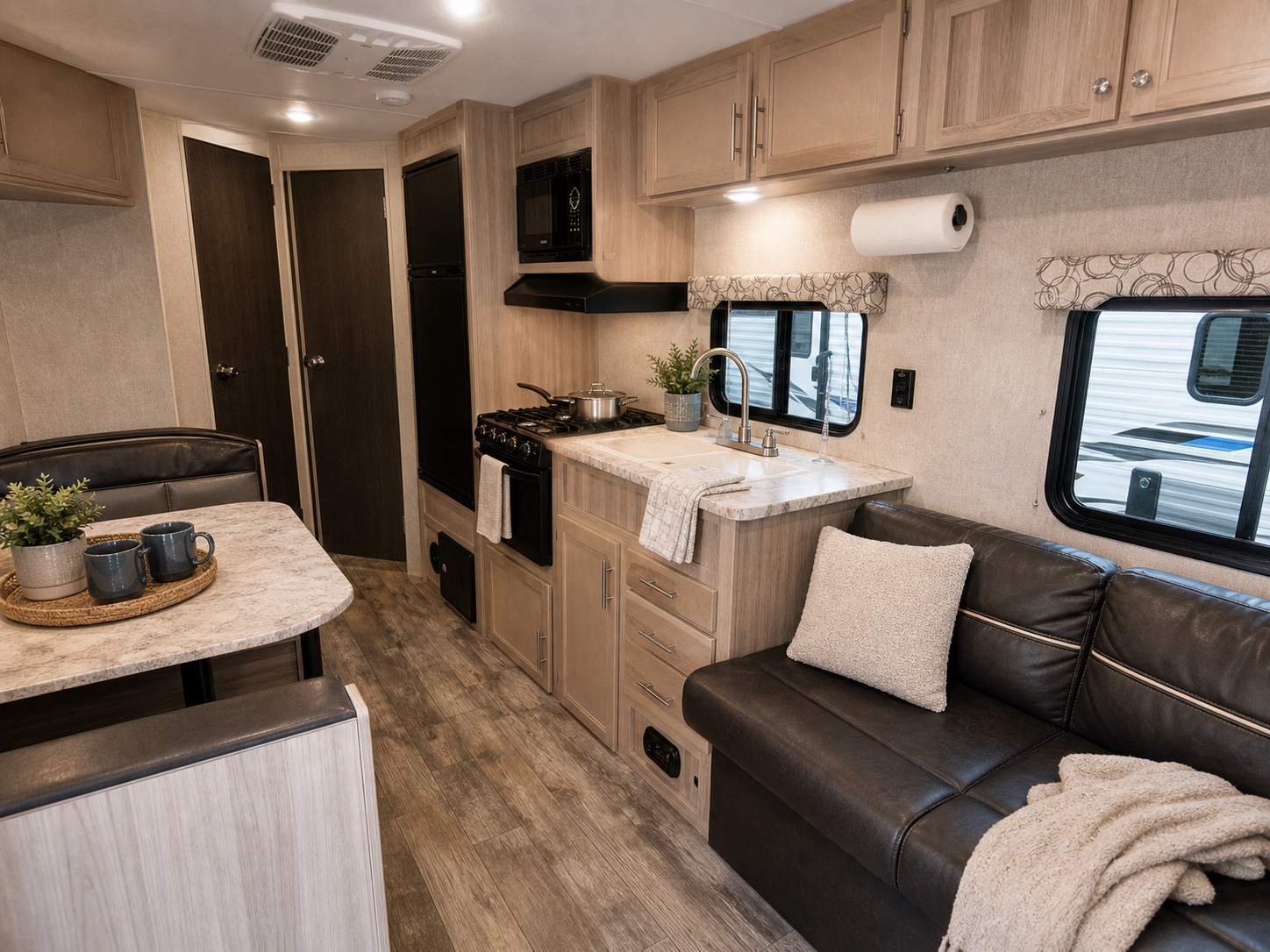 Staged Coachmen Catalina interior with black sofa, compact kitchen, and clean guest-ready details